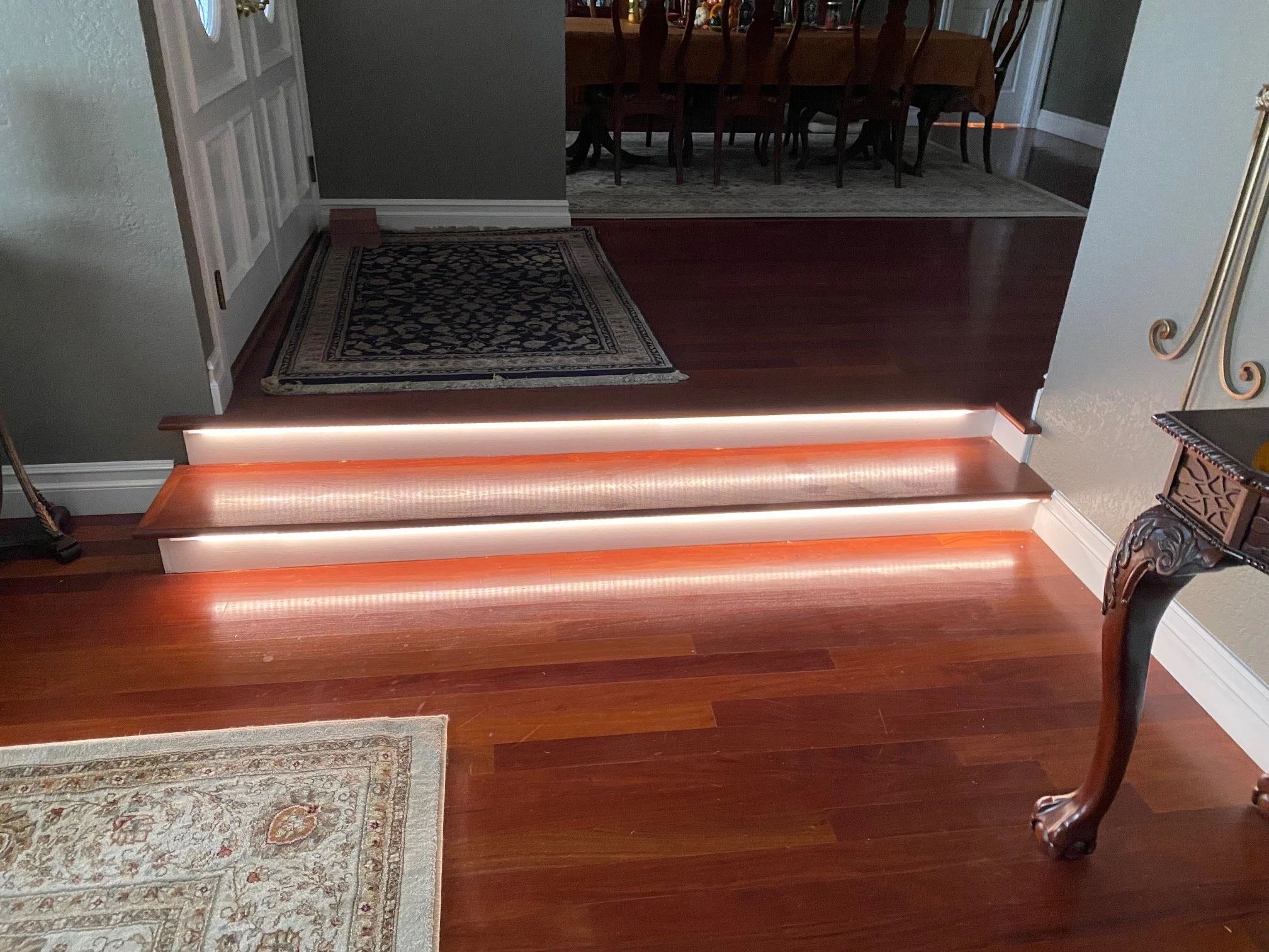 Entry steps in a remodeled home with lighting recessed into each stair nosing and refinished hardwood floors.