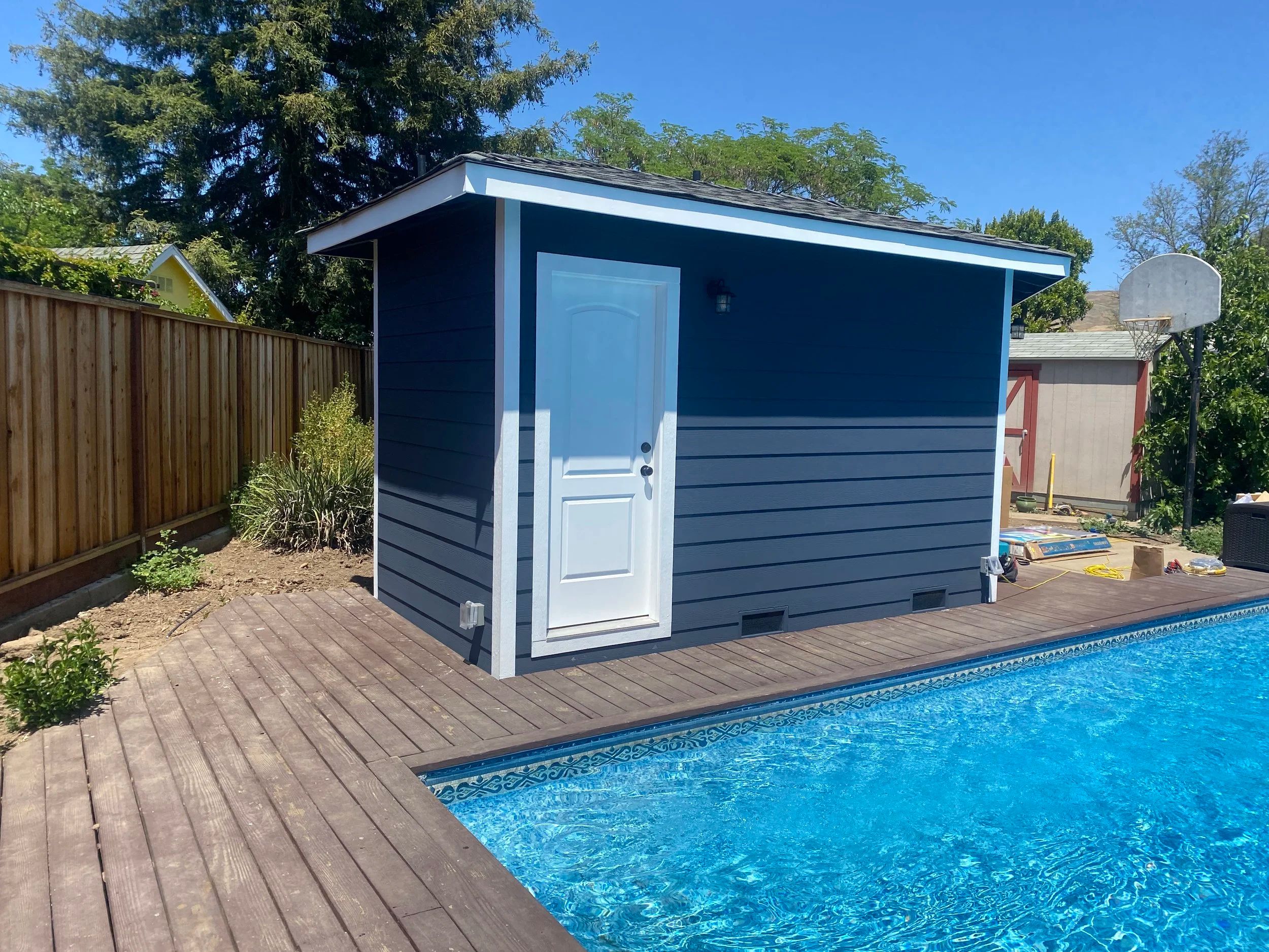 The same poolside building seen from the deck, showing the timber decking that runs to the edge of the pool.